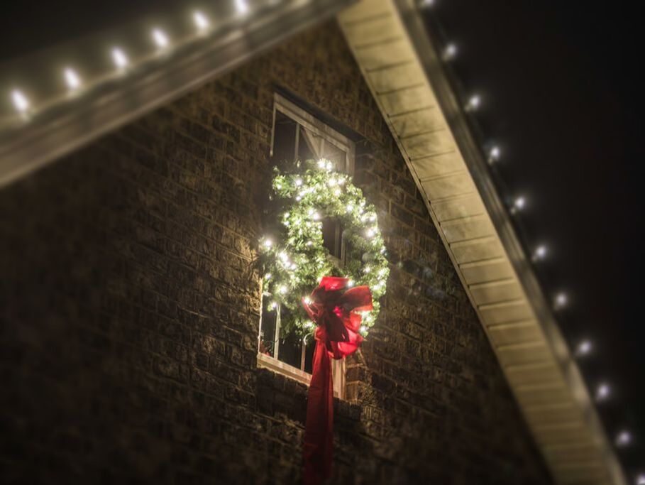 Lit Christmas wreath on a house