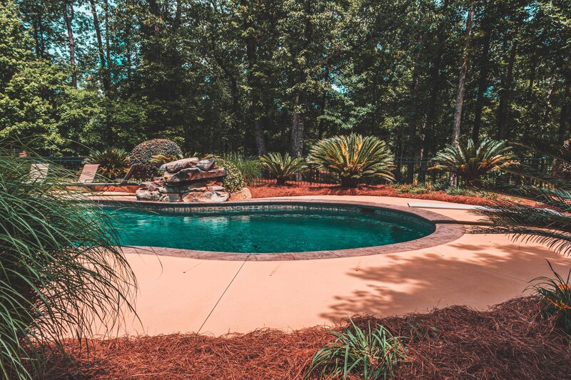 New pinestraw installed in flowerbeds around a pool patio