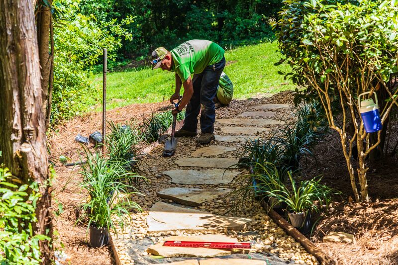 Worker installing an egg rock and flagstone path